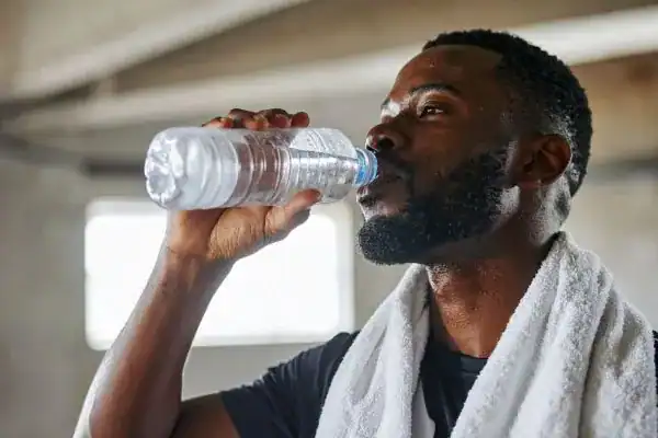Hydration: The Secret Ingredient for a Toned Stomach and Enhanced Fitness 1 Image of man drinking water to improve hydration Kenilworth after work out.